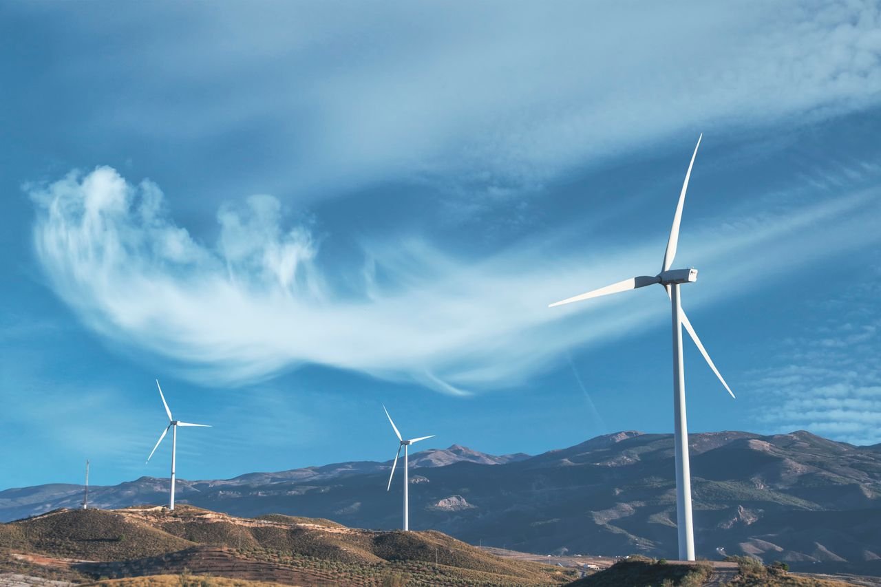 about-02 Wind turbines on a hillside capturing clean energy under a serene blue sky.